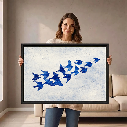 Cobalt Blue Swallows artwork held in a black frame by a woman beside a cream sofa.