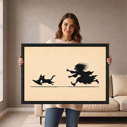 Funny Witch Cat Chase artwork held in a black frame by a woman beside a cream sofa.