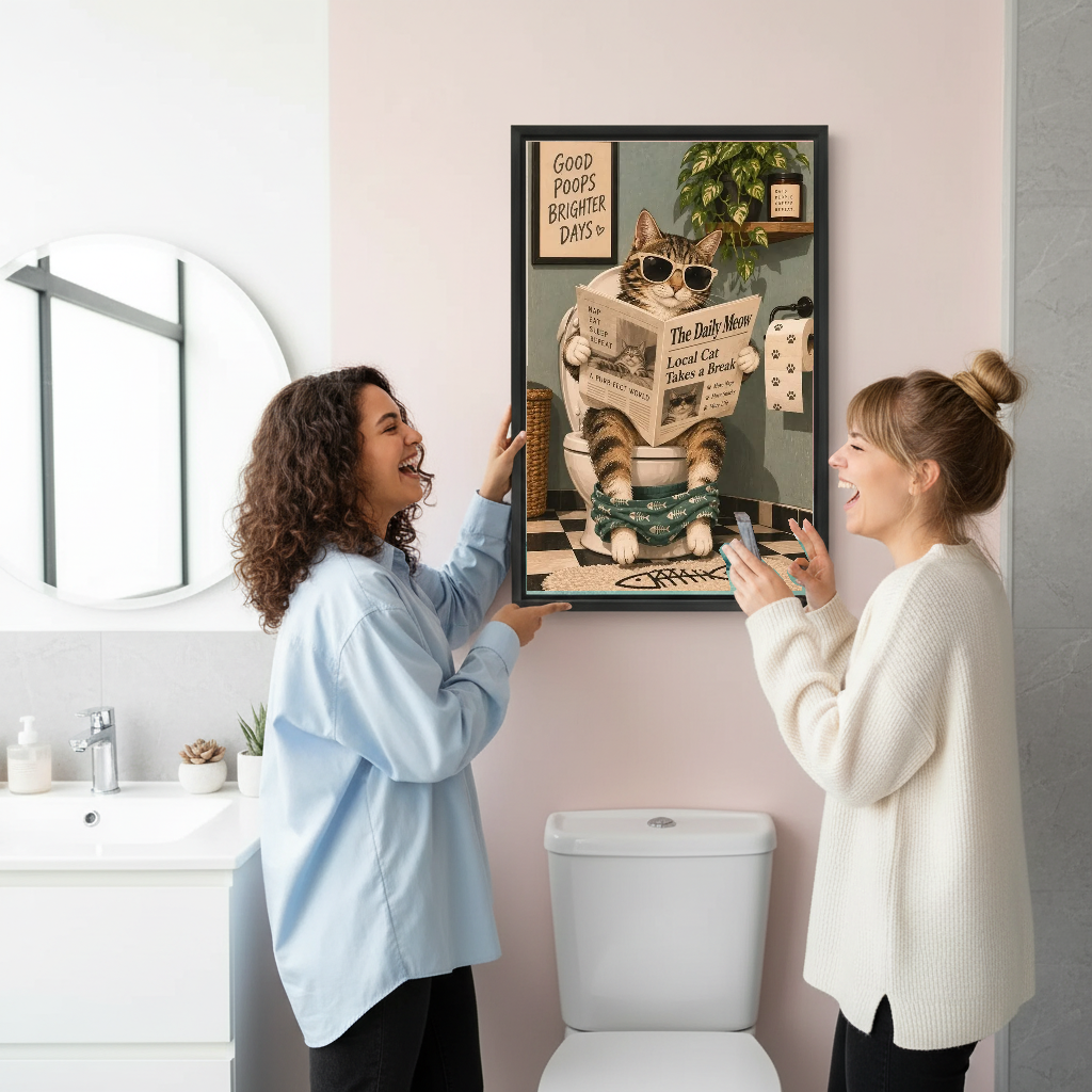 Funny Newspaper Bathroom Cat artwork held in a black frame by women in a bright bathroom.