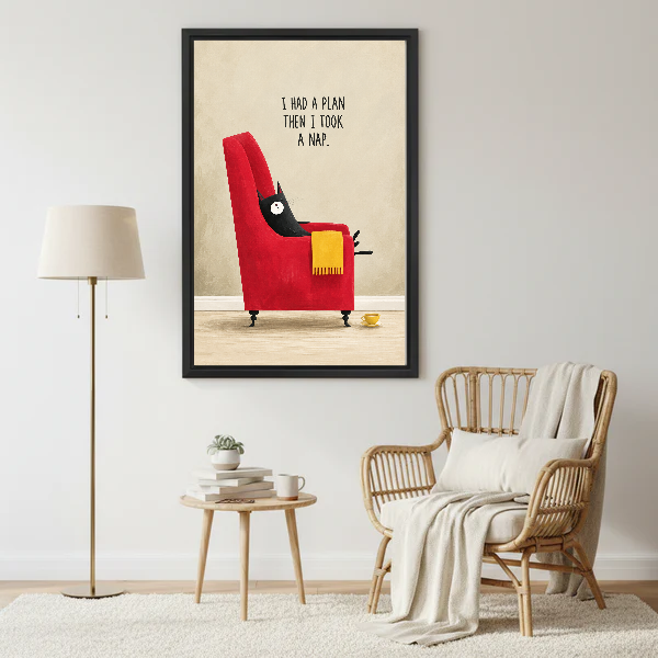 funny napping cat canvas wall art framed beside a wicker armchair with floor lamp and small table.