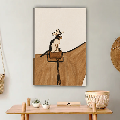 cowboy saddle cat canvas wall art unframed above a light wood console with cacti and basket.