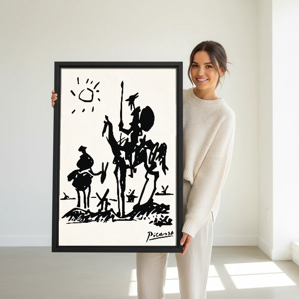 Don Quixote Canvas Wall Art held in a black frame by a standing woman in white.