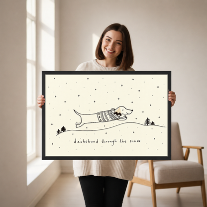 Dachshund Snow Canvas Wall Art held in a black landscape frame by a standing woman.