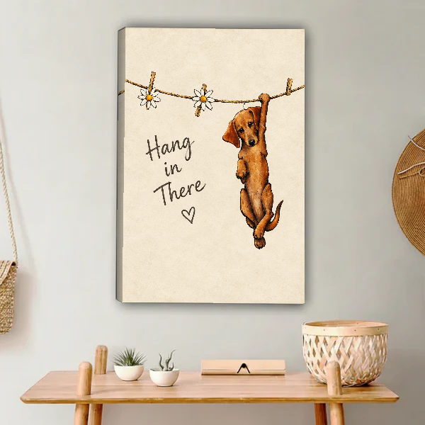 Hang In There Canvas Wall Art unframed above a light wood console and woven basket.