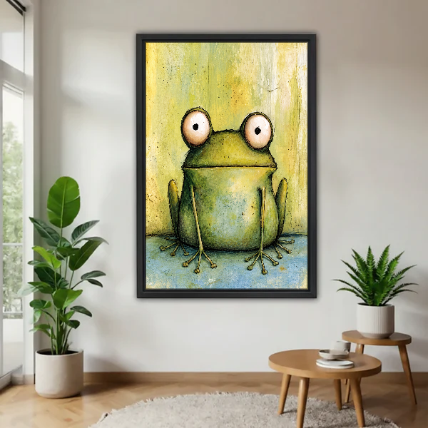 Wide Eyed Frog Canvas Wall Art framed above a pale wood table beside green plants.