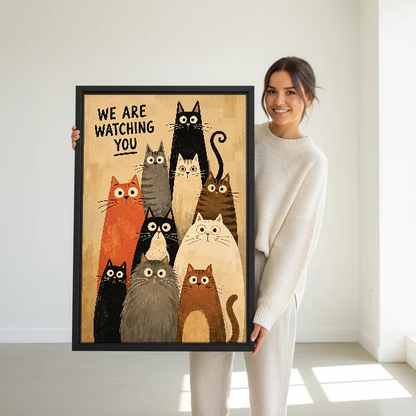We Are Watching Cats Canvas Wall Art held in a black frame by a woman in cream.