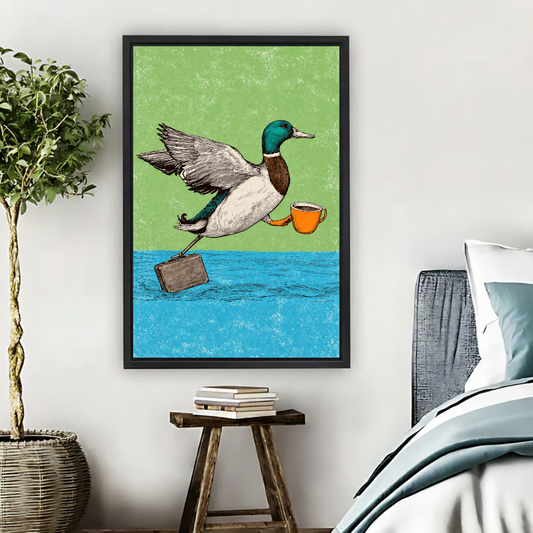 Coffee Commuter Duck Canvas Wall Art framed above pale blue bedding beside books and plants.