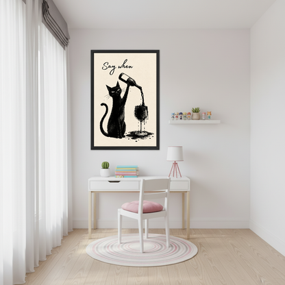 Say When Wine Cat Canvas Wall Art framed above a white desk beside a pale pink chair.