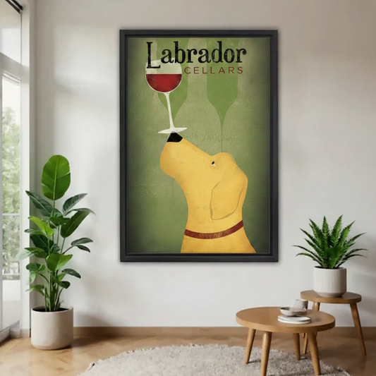 Vintage Labrador Cellars framed wall art of a yellow Lab nose-balancing a red wine glass, mounted on a white wall flanked by two green potted plants