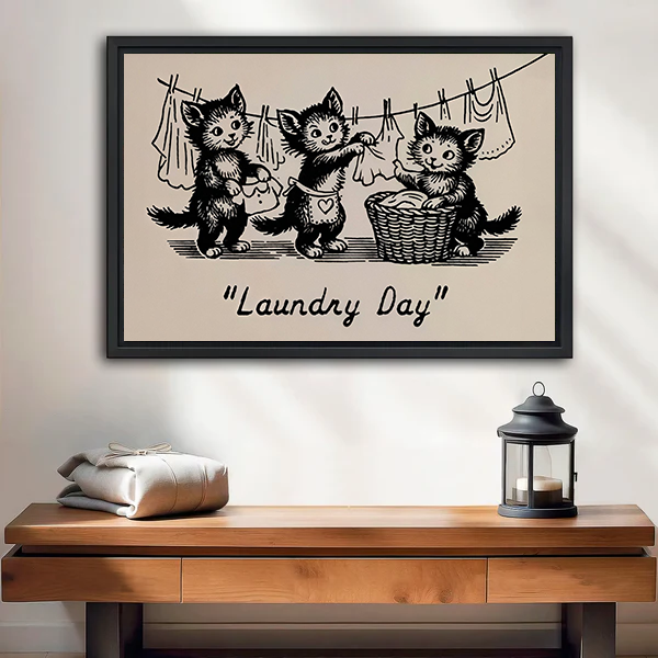 Framed Laundry Day kittens canvas wall art with vintage black linework above a bed with white bedding.