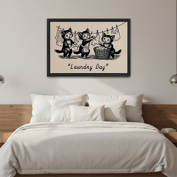 Black-framed Laundry Day kittens canvas wall art above a wooden console with folded blankets and a lantern.