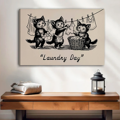 Vintage Laundry Day kittens canvas wall art in a black frame above a cream sofa with wooden armrests.