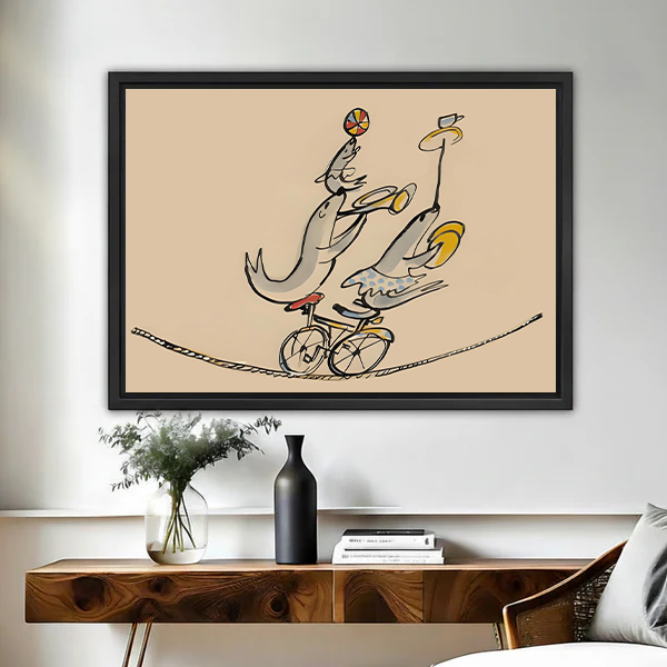 Line art circus fish canvas wall art in black float frame above wooden console, three fish cycling on tightrope with ball and banana, warm sand background