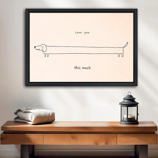 Framed love you this much dachshund canvas wall art with minimalist black linework displayed above a wooden console table.