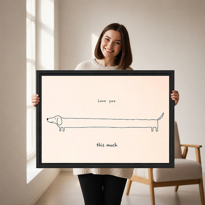 Woman holding framed love you this much dachshund canvas wall art with delicate dog linework on a cream background.