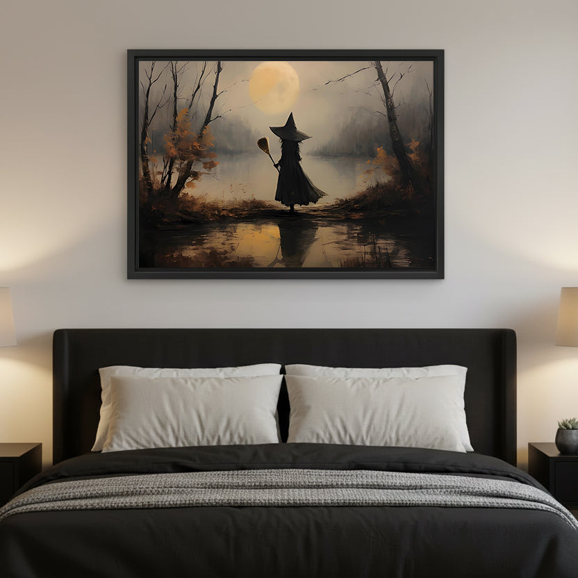 Framed witch silhouette full moon wall art hanging above a black upholstered bed with white pillows