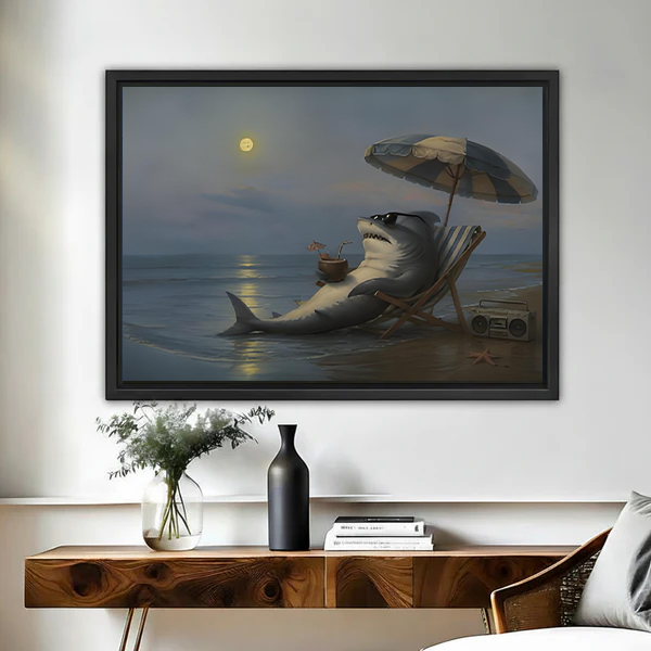 Black-framed moonlit beach shark canvas wall art above a bed, depicting a shark relaxing beneath an umbrella.