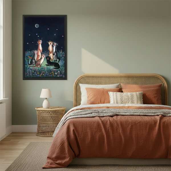 Moonlit cats canvas wall art in a black frame beside a rattan bed with warm terracotta bedding.