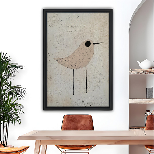 Woman holding black-framed minimalist neutral bird canvas wall art featuring a speckled beige bird on a cream background.