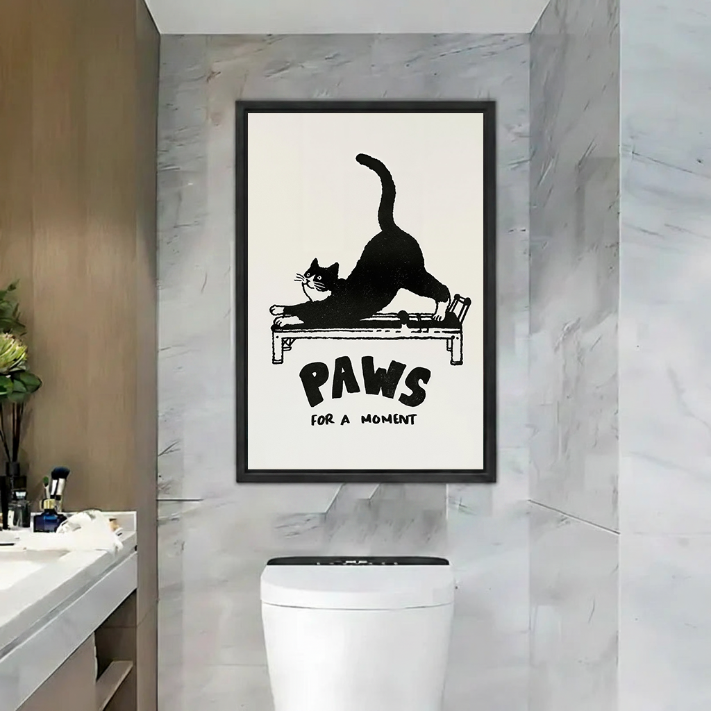 Gallery-wrap Paws for a Moment cat canvas wall art with a stretching black cat displayed above a bathroom toilet.