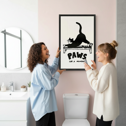Framed Paws for a Moment cat canvas wall art displayed beside a round mirror and wooden bathroom vanity.