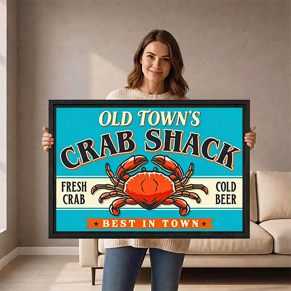 Smiling woman holding framed retro crab shack sign wall art with orange crab and cold beer text