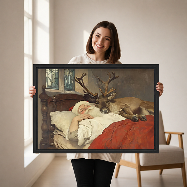 Black-framed Santa and reindeer canvas wall art above a wooden console, showing Santa resting beside an antlered reindeer.