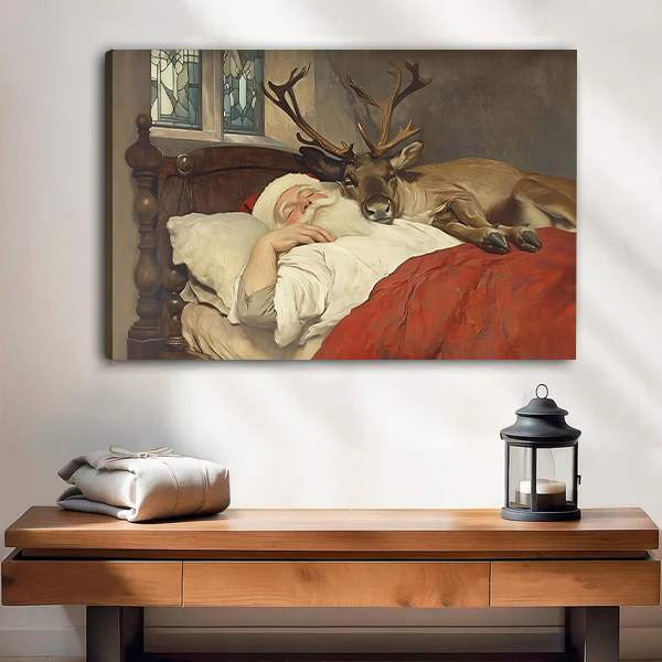 Woman holding black-framed Santa and reindeer canvas wall art depicting a cozy bed scene with a red blanket.