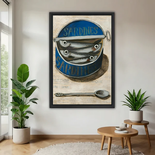 Framed vintage sardine tin canvas wall art with a blue can and spoon, displayed between green houseplants.