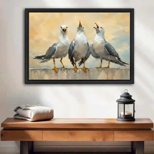 Three seagulls oil painting framed canvas wall art with birds calling on stone wall, warm golden sky background, displayed above wooden console table with grey linen and black lantern