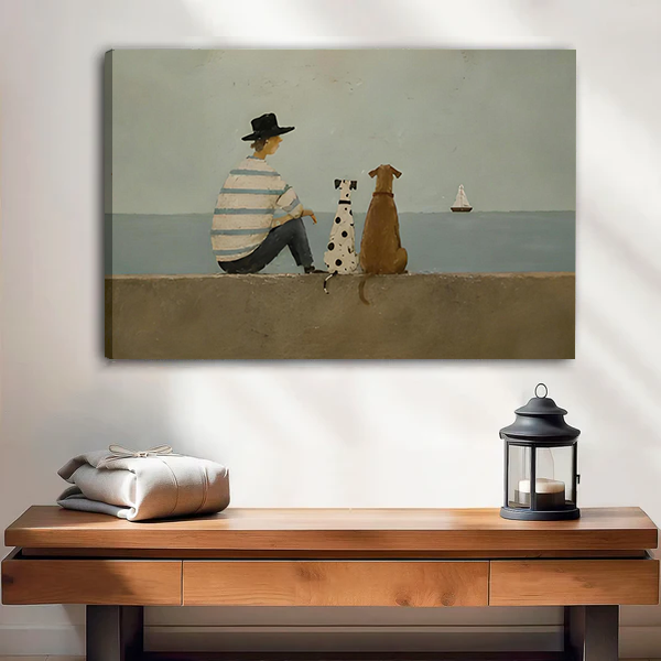 Woman holding framed seaside dogs canvas wall art showing a striped-shirt figure and two dogs facing the sea.
