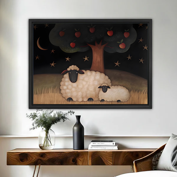 Woman holding black-framed sheep and apple tree canvas wall art featuring a sheep and lamb beneath a starry sky.