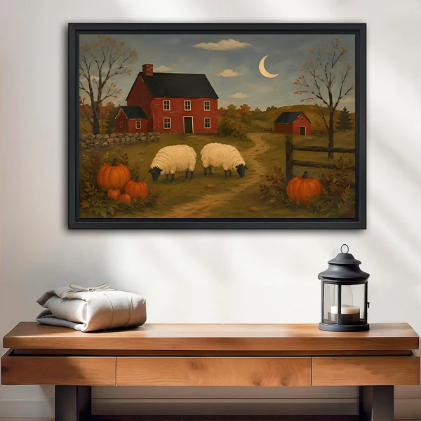Framed sheep farm canvas wall art with a red farmhouse and crescent moon hangs above a wooden console.