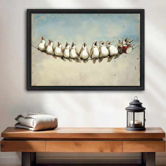 Black framed wall art print of a row of singing white birds on a wire with a drummer bird, displayed above a wooden console table in a warm entryway