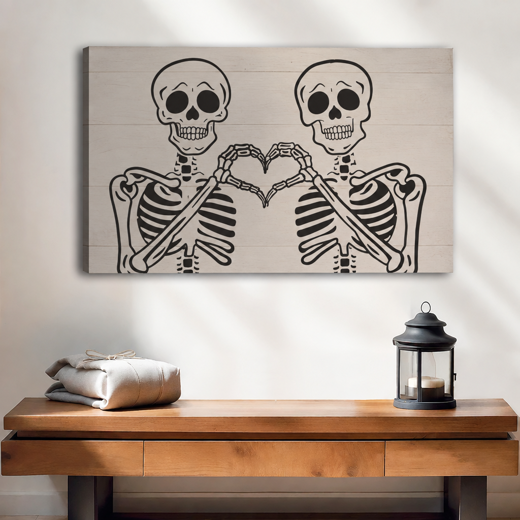 Frameless gallery wrap canvas of two skeletons forming a heart with their hands on a white shiplap background above walnut console table with lantern and linen bundle