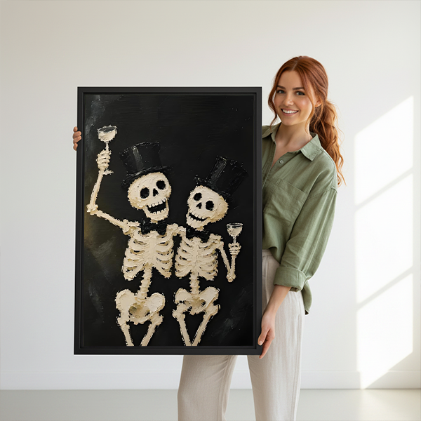 Black framed skeleton toast canvas wall art featuring two smiling skeletons, displayed between houseplants above wooden tables.