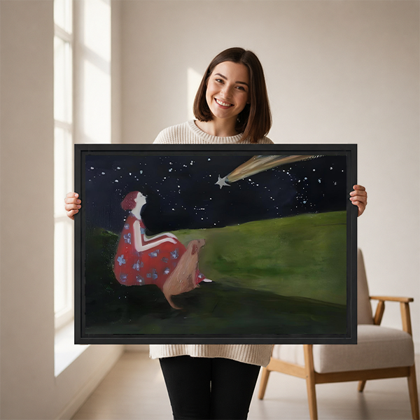 Woman holding a large framed stargazing girl and deer wall art print showing a shooting star night scene, demonstrating print scale and black frame detail