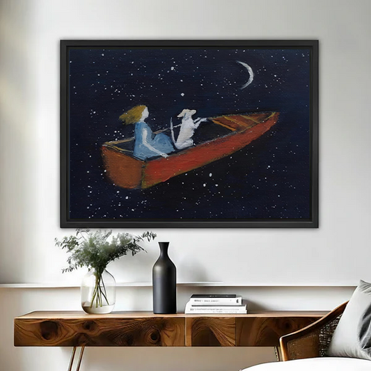 Dreamy starry night framed wall art print of a girl and white dog rowing a red boat under a crescent moon, hung above a wooden console table