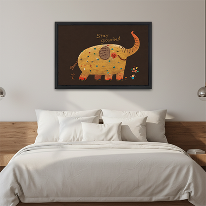 Folk art Stay Grounded elephant canvas wall art in a black frame above a cream sofa with wooden arms.