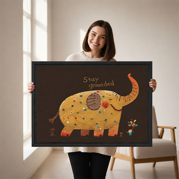 Framed Stay Grounded elephant canvas wall art above white bedding and a wooden headboard in a neutral bedroom.