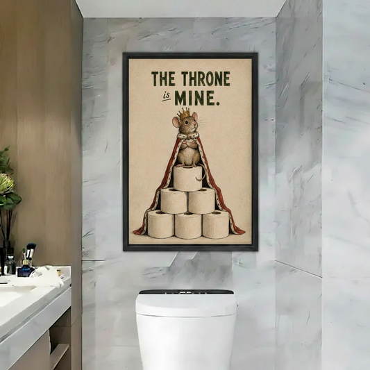Black framed poster of a royal mouse wearing a crown and cape perched on stacked toilet rolls with "The Throne is Mine" quote, hung above toilet in a luxury marble bathroom