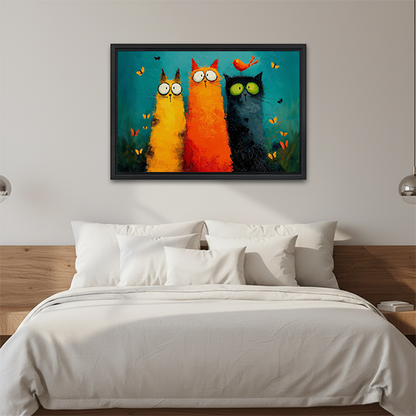 Black-framed three cats canvas wall art with a perched orange bird displayed above a white bed.