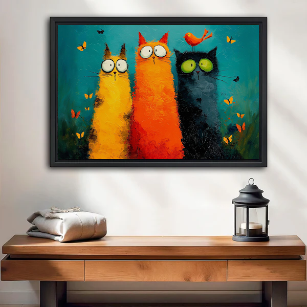 Unframed whimsical three cats canvas wall art with a teal background above a wooden console and lantern.
