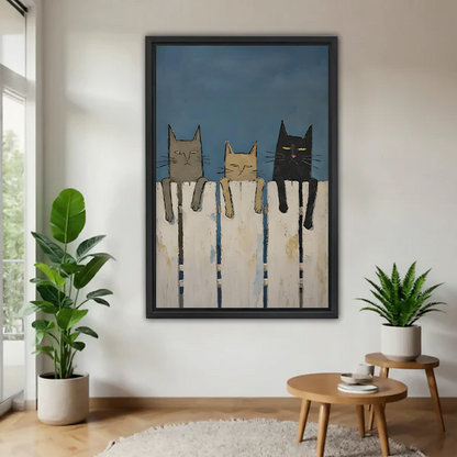 Framed canvas wall art featuring three whimsical cats sitting on a white picket fence against a dark blue sky, displayed in modern living room