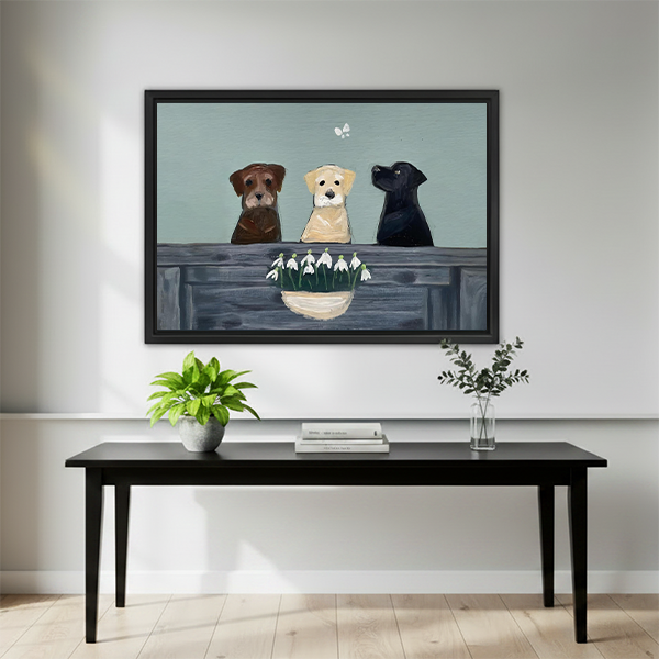 Three Labs with snowdrop flowers framed canvas art hung above black bench table in bright entryway