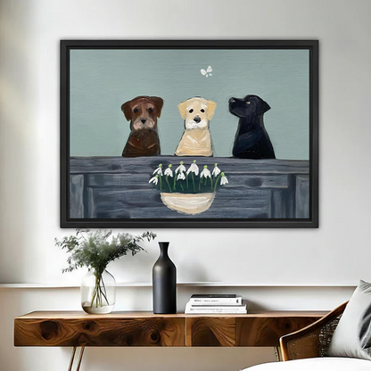 Three Labrador dogs with snowdrop flowers framed canvas wall art in black float frame above wooden console