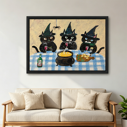 Black framed three witch cats canvas wall art above a wooden console with folded blankets and a lantern.