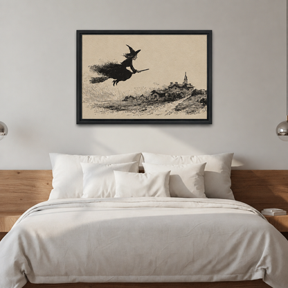Black-framed vintage flying witch wall art above a bed with white bedding and a wooden headboard.