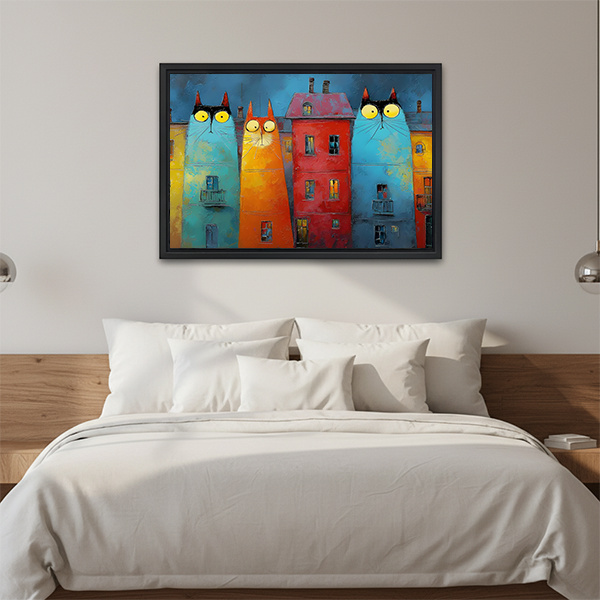 Framed whimsical cat buildings canvas wall art with colorful facades above a wooden sofa with cream cushions.