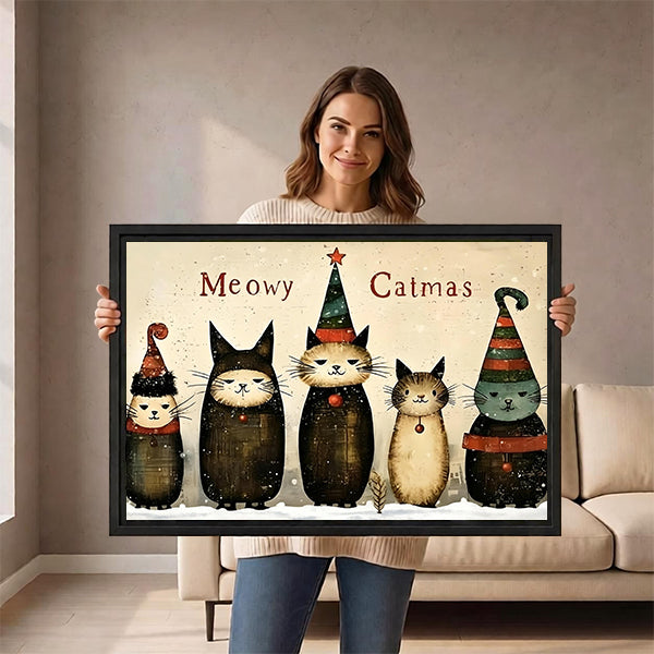 Woman holding framed whimsical Christmas cats canvas wall art with five hat-wearing cats in a living room